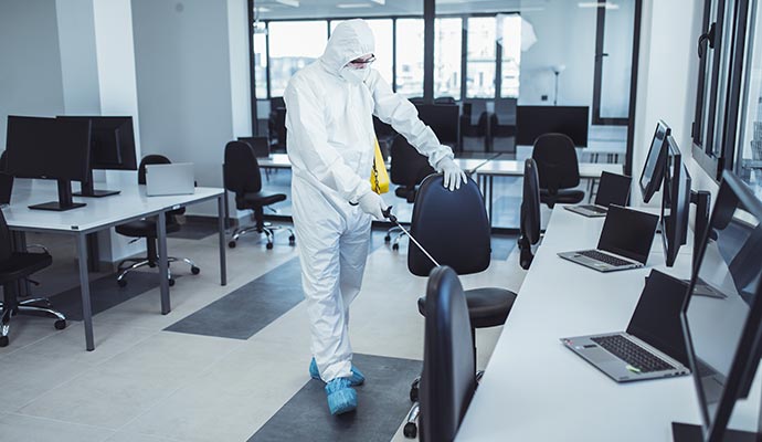 Person sanitizing an office chair in a modern office
