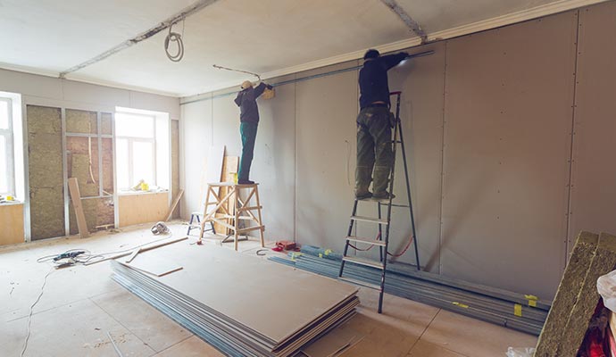 Person installing drywall in a room