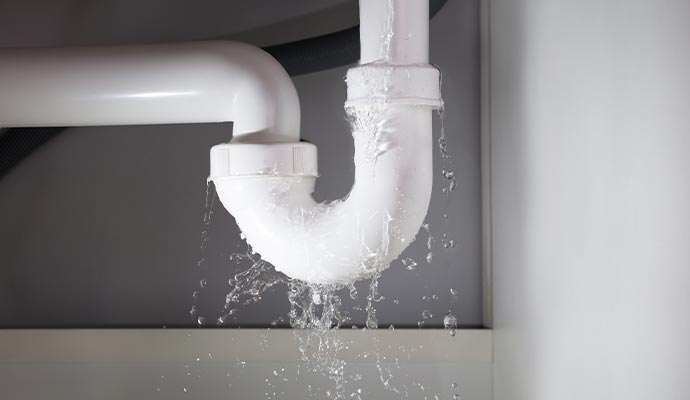 A PVC pipe leaking water under the sink