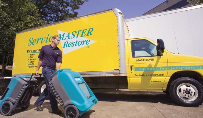 A ServiceMaster Restore truck parked in front of a house