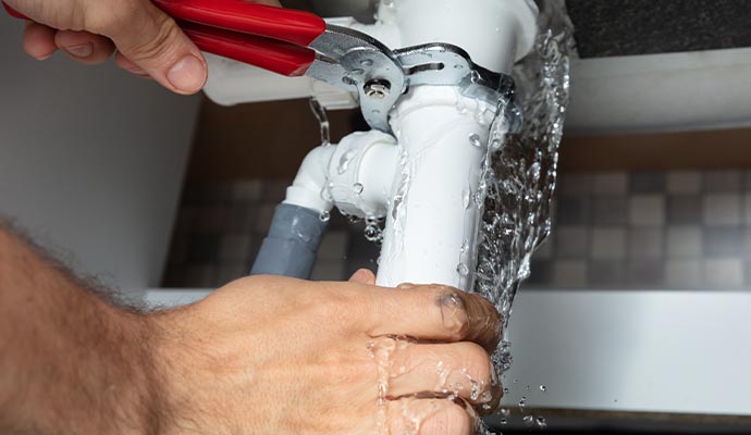 Person repairing water pipe with equipment